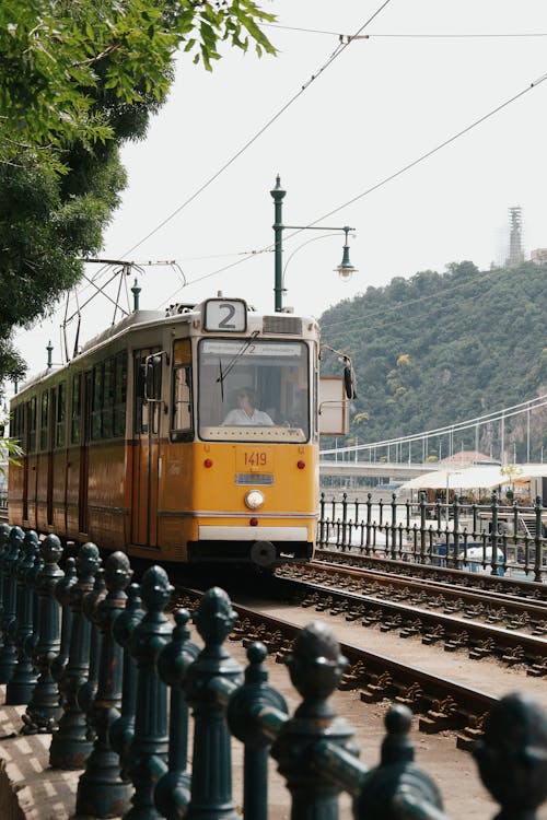 Free A yellow tram on a track next to a bridge Stock Photo