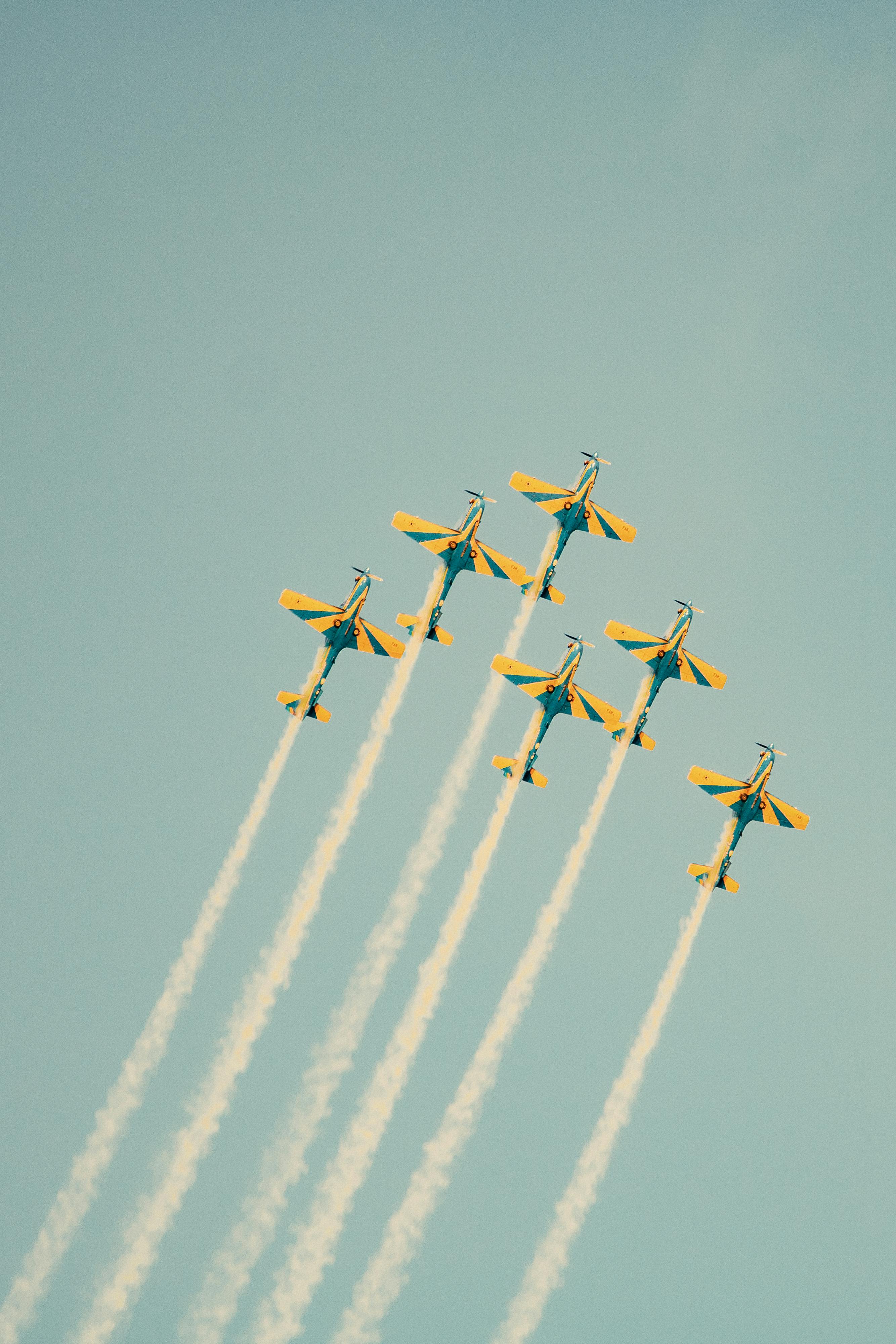 Vibrant aerobatic planes performing a precision airshow against a clear blue sky.