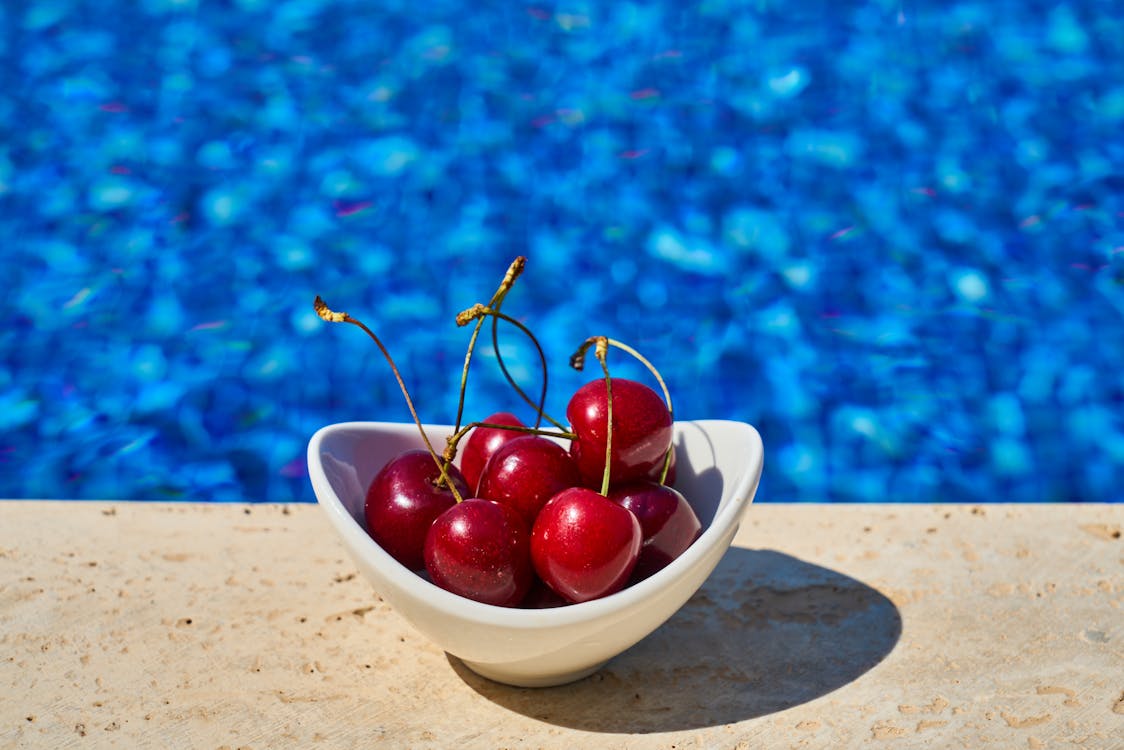 bowl of cherries in front of a pool in the summer