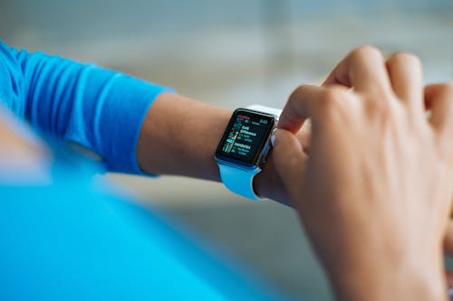 Person in Blue Long Sleeve Shirt Using Smart Watch