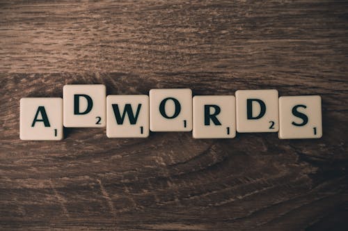 Free Scrabble Forming Adwords on Brown Wooden Surface Stock Photo