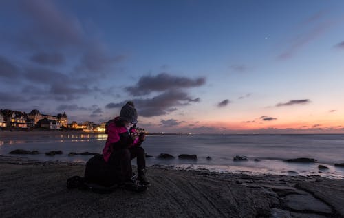 Person Sitting on Rock Near Water