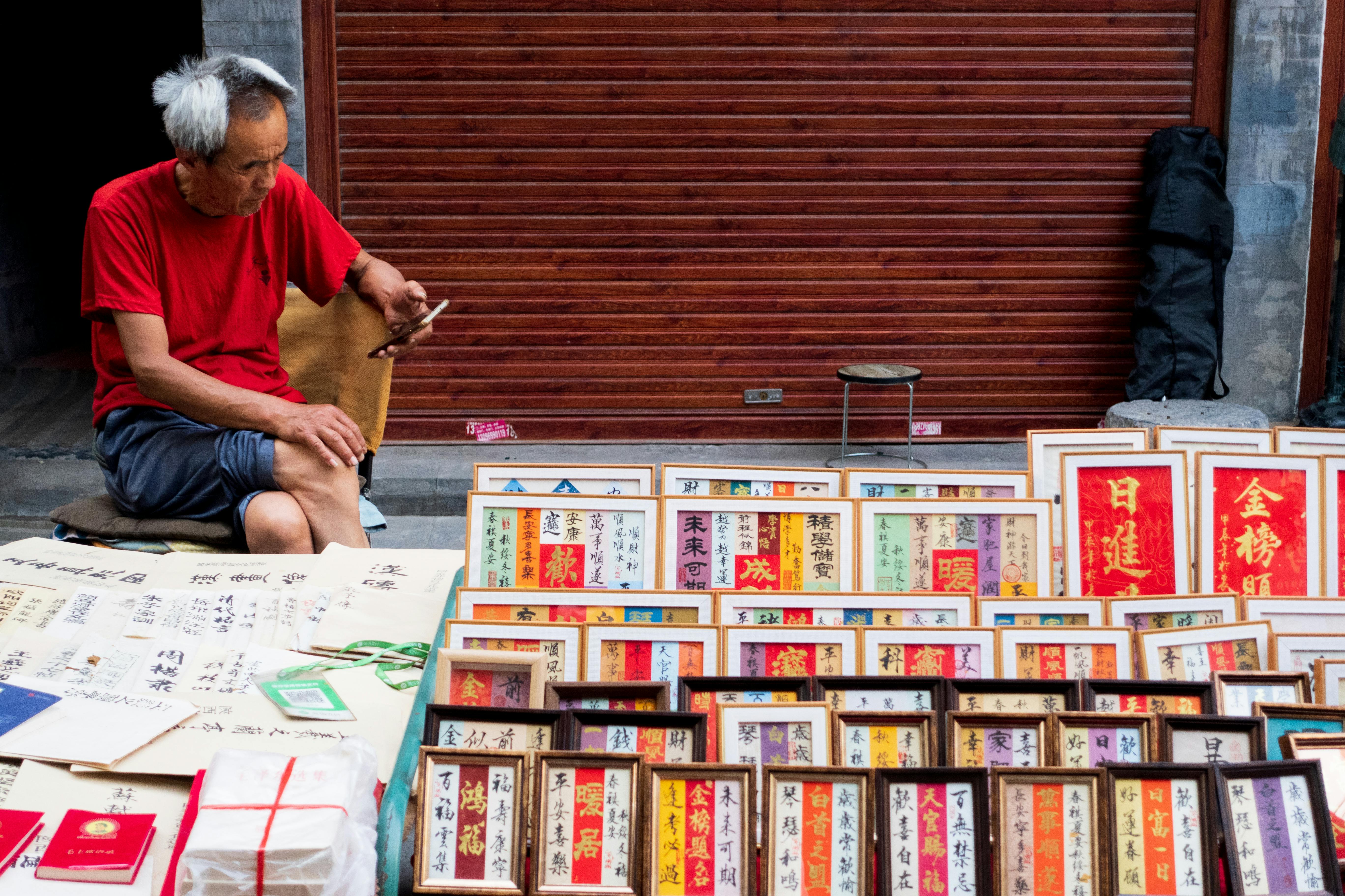man sitting with smartphone at bazaar