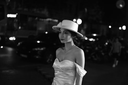 Free Stylish woman in a white dress and hat posing gracefully at night. Stock Photo
