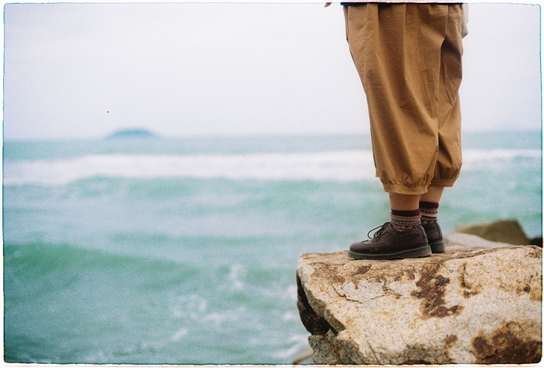 Person standing on a rock at the shore of Nha Trang, Vietnam, overlooking the sea.