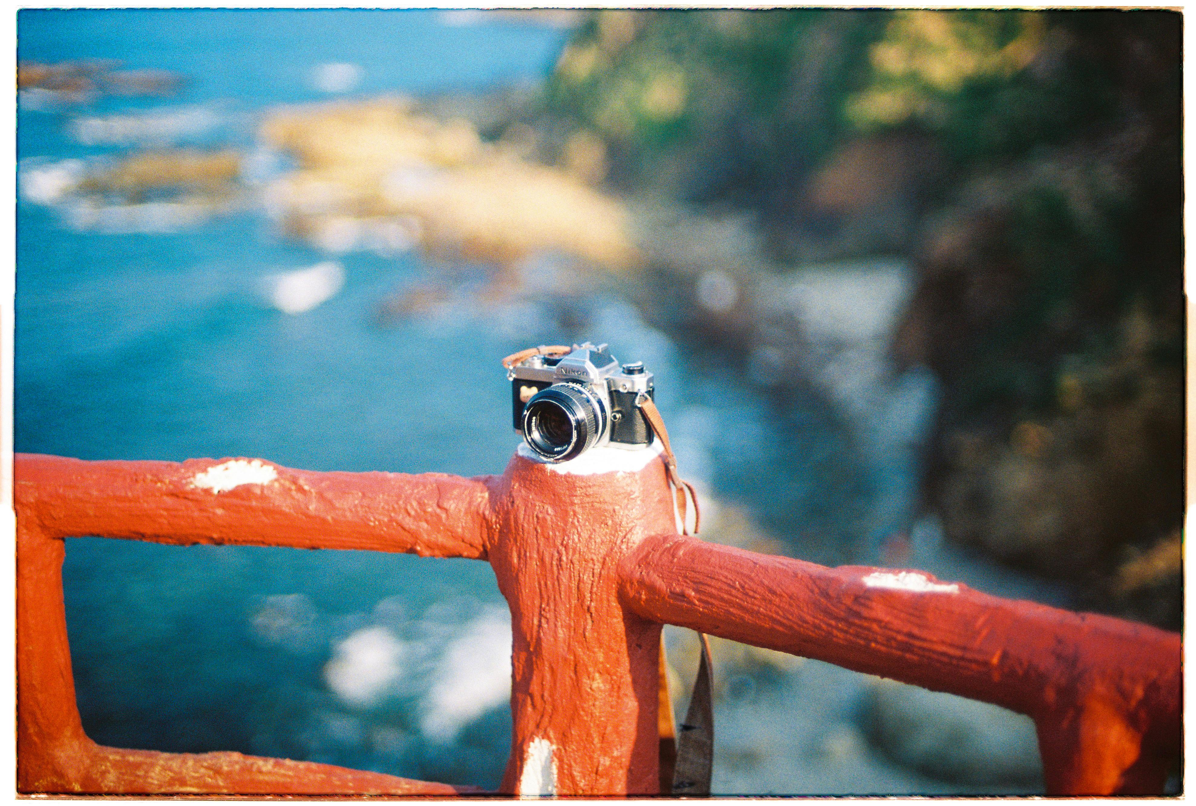 A vintage camera rests on a red railing overlooking the scenic coast of Bình Định, Vietnam.