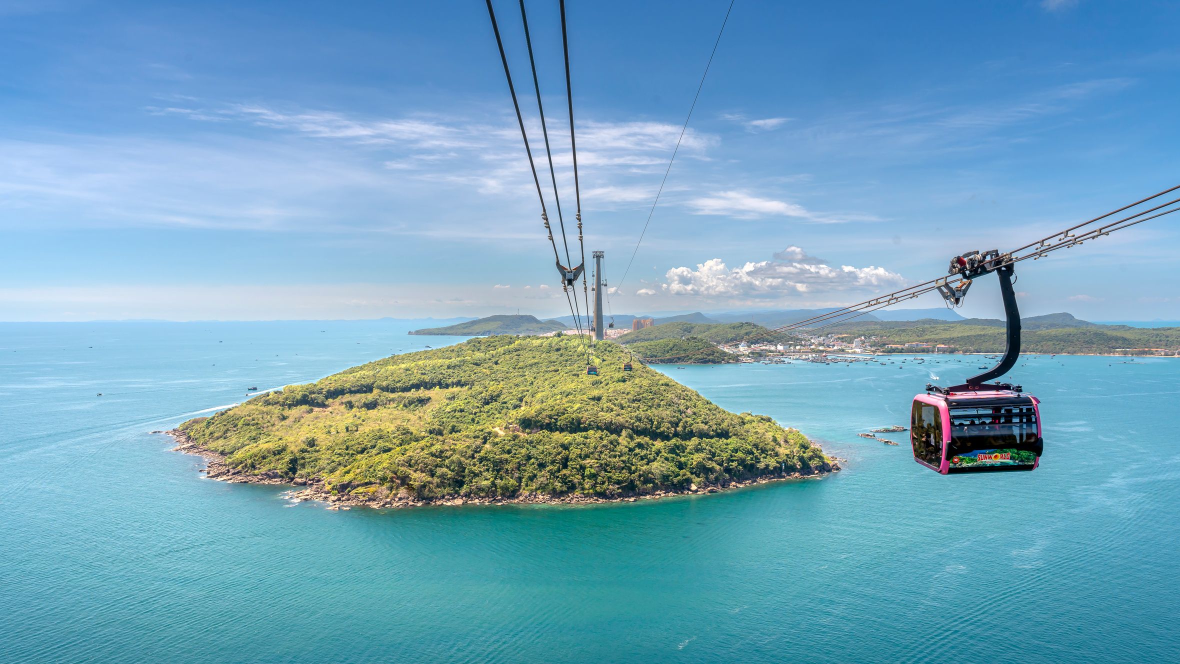 Stunning aerial view of a cable car crossing over Thom Island with clear blue waters in Vietnam.