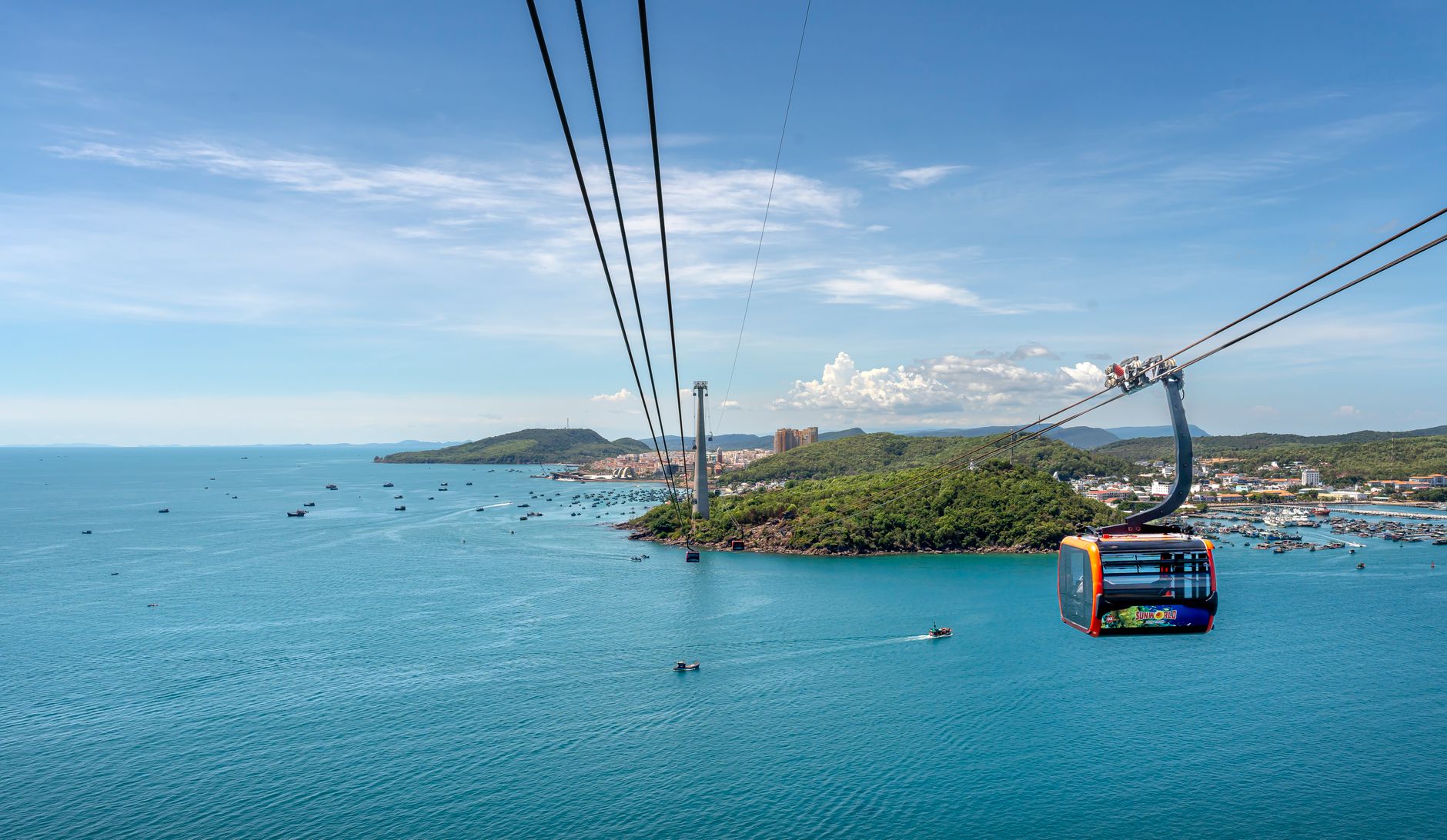A stunning view of a cable car over the vibrant blue ocean with lush islands in Vietnam.