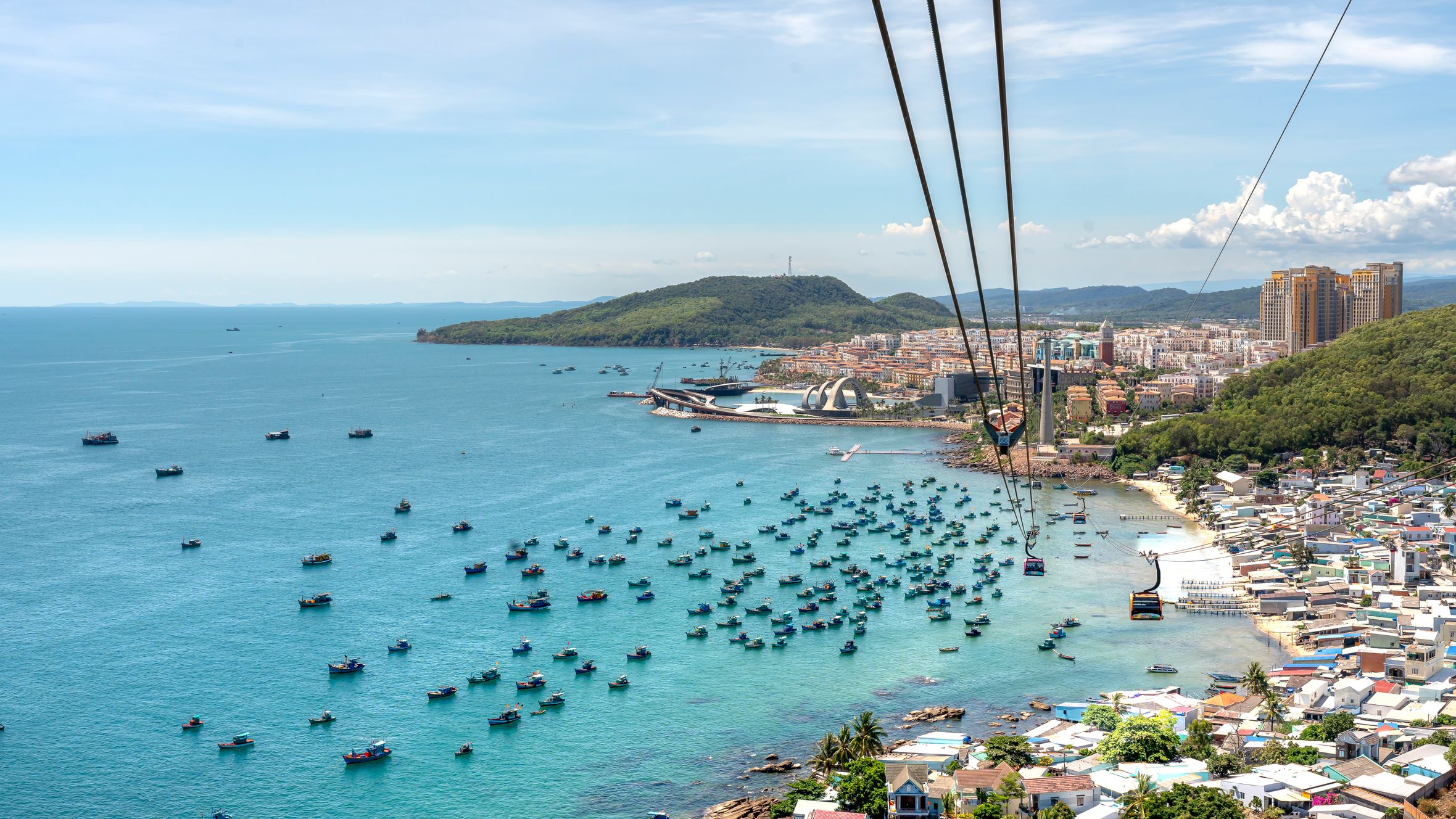 A breathtaking aerial view of Phu Quoc Island with boats, coastline, and cable car over blue water.