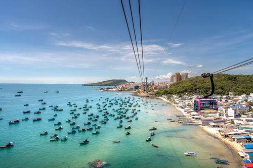 Free A breathtaking aerial view of a cable car soaring over a vibrant seascape in Vietnam, surrounded by colorful boats and lush landscapes. Stock Photo