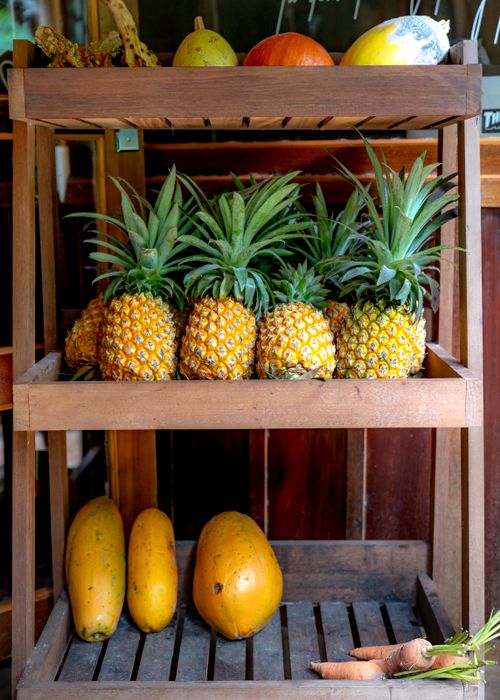 Free Colorful tropical fruits displayed on rustic wooden shelves in a cozy indoor setting. Stock Photo