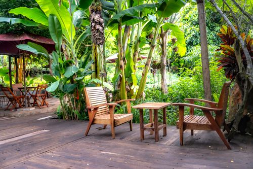 Free Wooden chairs and table in a lush tropical garden setting. Stock Photo