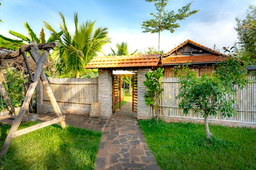 Free Inviting garden entrance featuring a wooden swing and lush greenery under a clear blue sky. Stock Photo