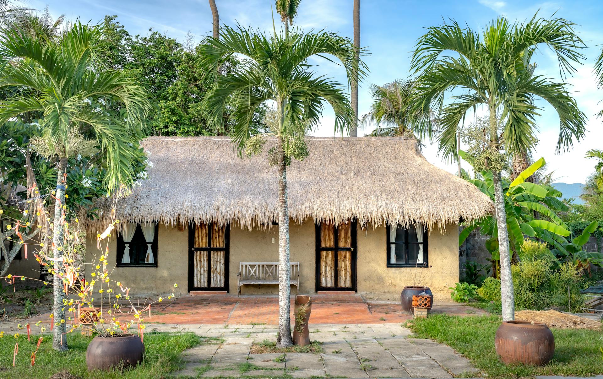 Palm Trees in front of House with Thatched Roof