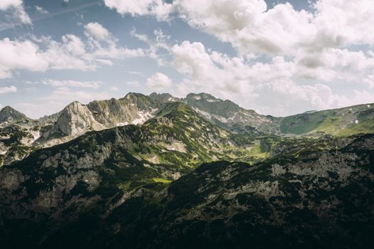 A stunning mountain landscape with lush greenery and soft clouds, captured from above.
