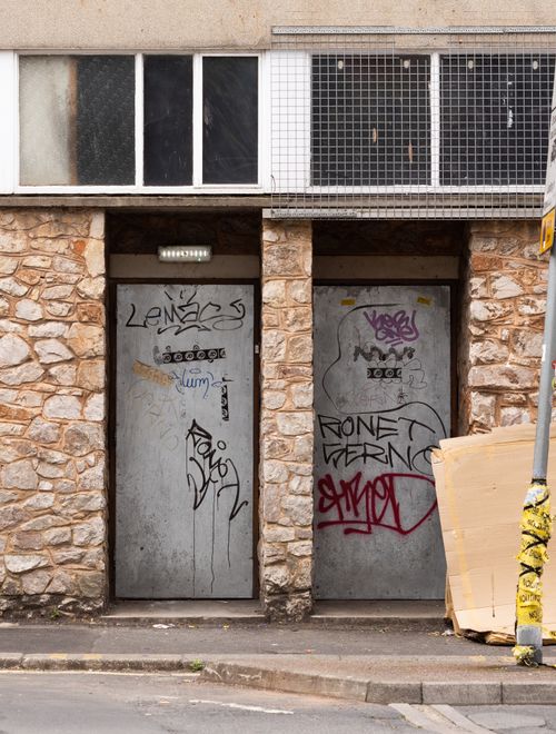 Free Graffiti-covered metal doors on an abandoned urban building with stone facade. Stock Photo
