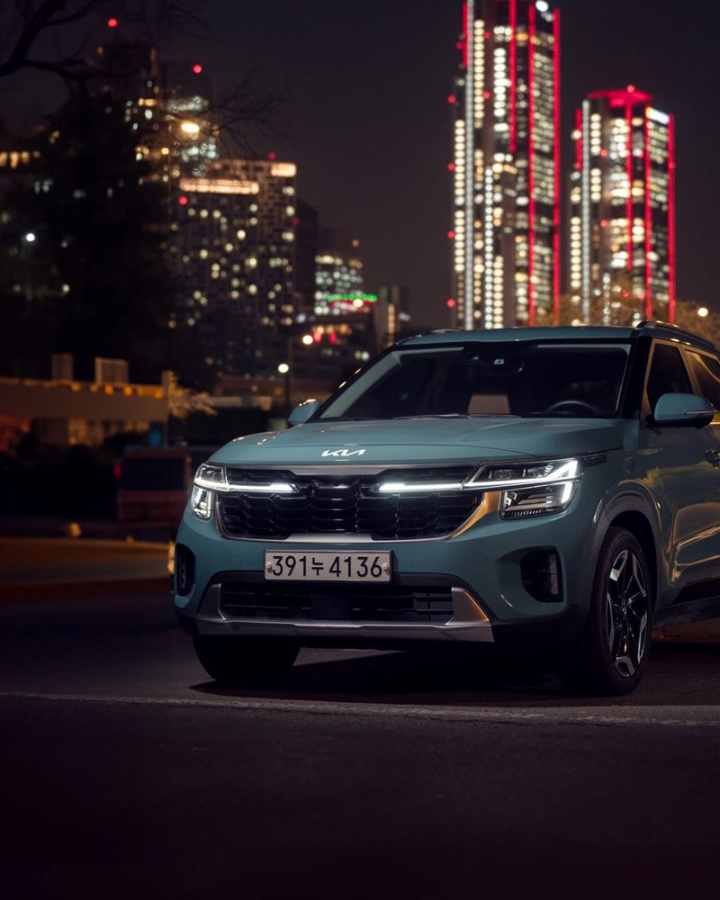Night view of a Kia SUV parked against a lit city skyline