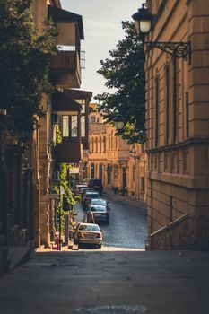 Scenic view of a historic cobblestone street in Baku, Azerbaijan, featuring vintage architecture and cars.