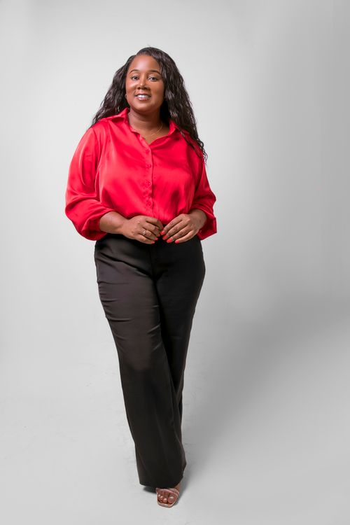 Free Portrait of a young African woman in a red shirt, smiling confidently against a white background. Stock Photo