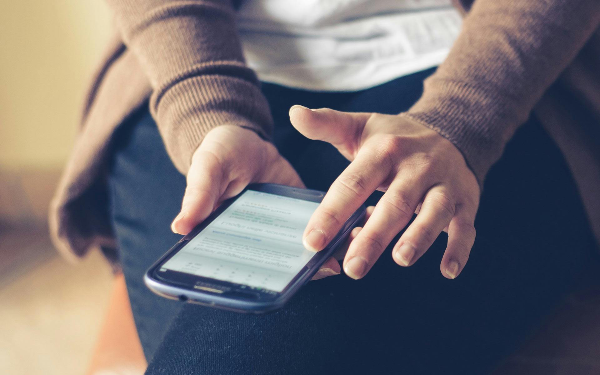 person holding smartphone while sitting