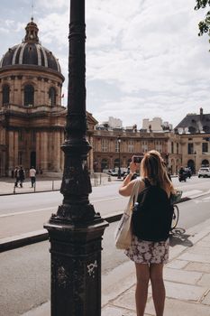 Woman taking a photo of the historic Institut de France in Paris, France.