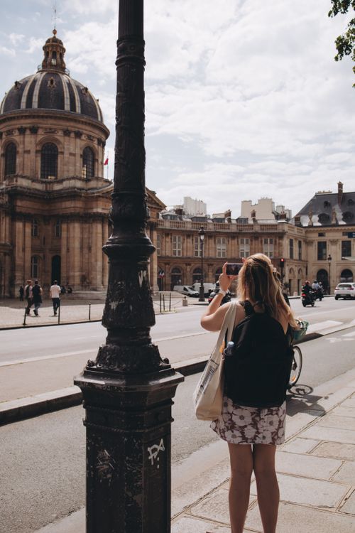 Free Woman taking a photo of the historic Institut de France in Paris, France. Stock Photo