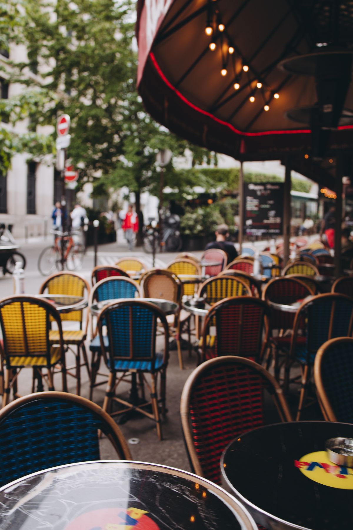 Terrasse de café parisienne typique, chaises colorées sur trottoir