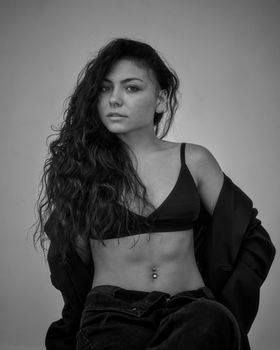 Stylish black and white portrait of a woman in lingerie posing confidently indoors.