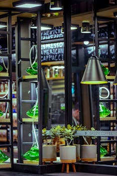 Modern café interior featuring green decor, mirrors, and potted plants in a stylish setting.