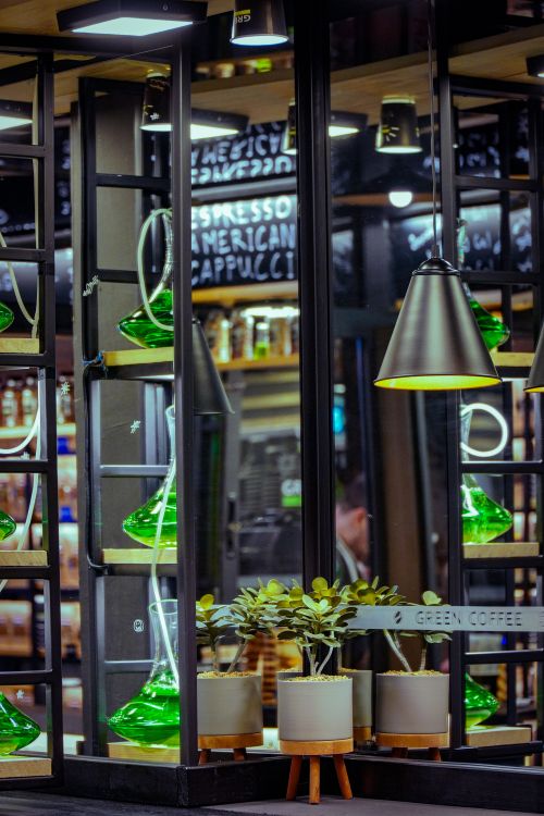 Free Modern café interior featuring green decor, mirrors, and potted plants in a stylish setting. Stock Photo