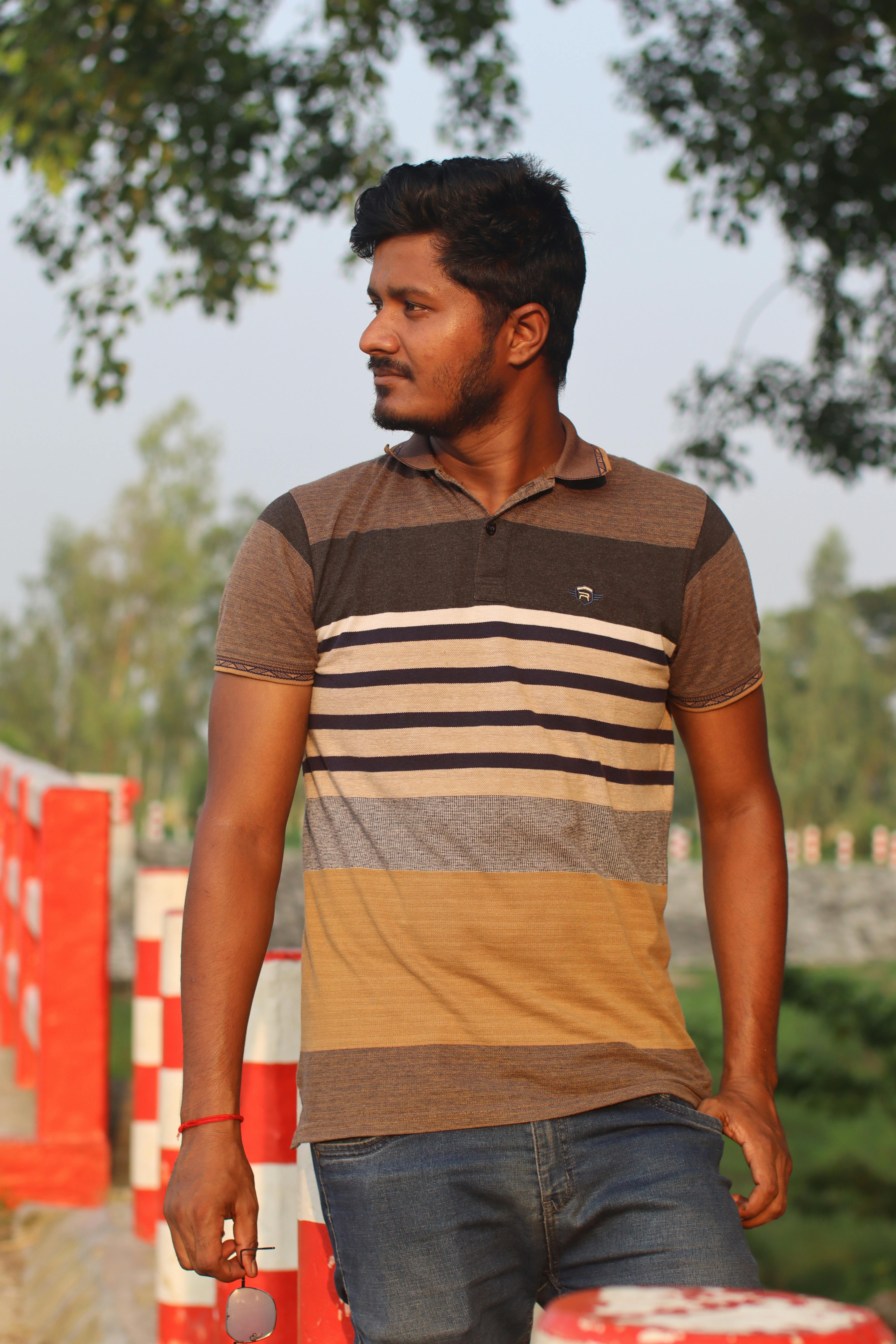 Portrait of a man with beard and mustache standing outdoors in a striped polo shirt.