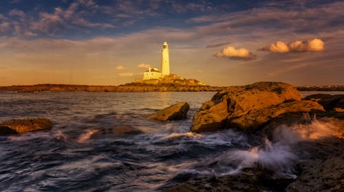 A lighthouse is seen in the distance on a rocky shore