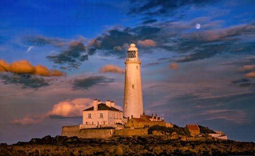 A lighthouse is shown at night with clouds