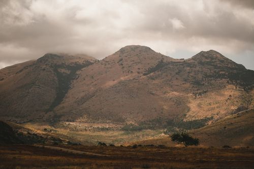 Free A stunning view of a dry mountainous landscape with a dramatic sky and isolated tree. Stock Photo