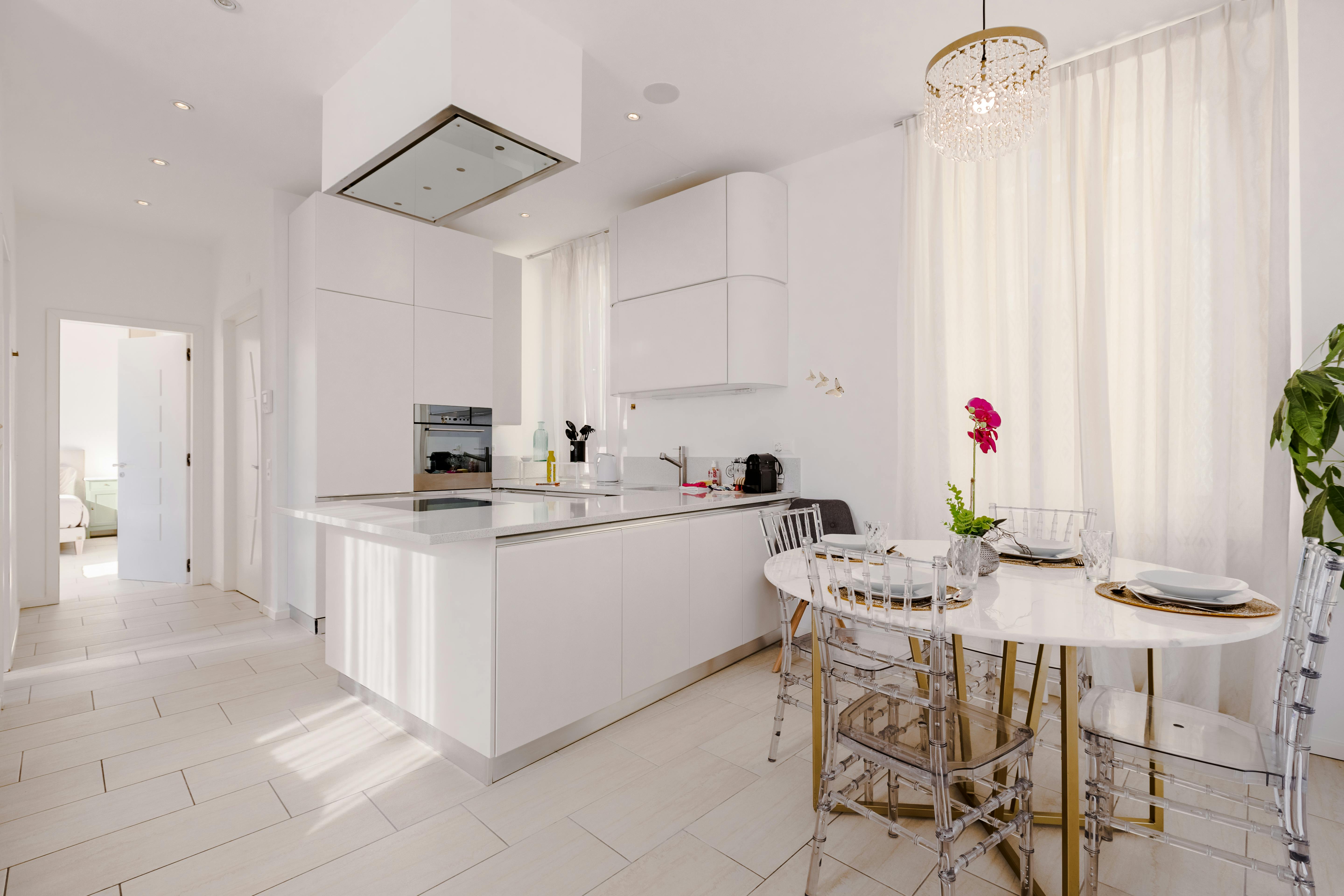 A white kitchen with a dining table and chairs