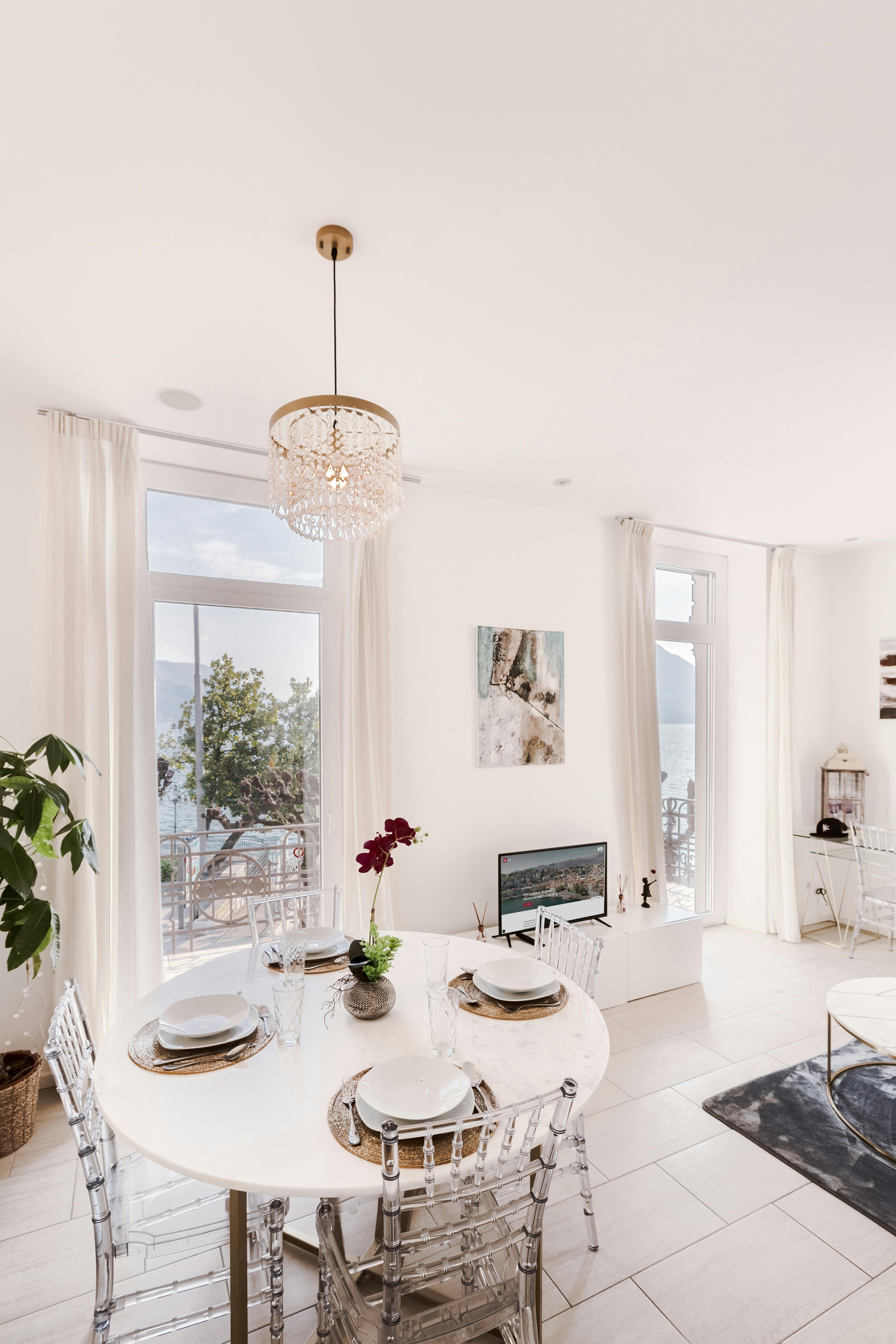 Bright and sophisticated dining area featuring acrylic chairs and a crystal chandelier.