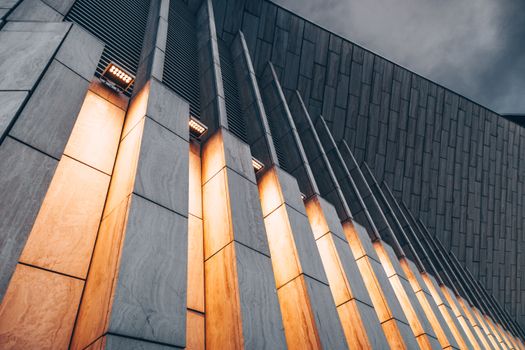Low angle view of modern architectural facade with glowing lights, capturing a dramatic and urban feel.