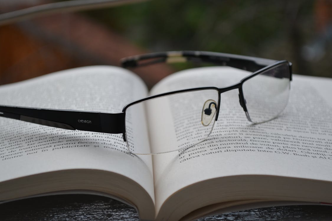 무료 열린 책에 검은 색 프레임이있는 투명 안경 스톡 사진