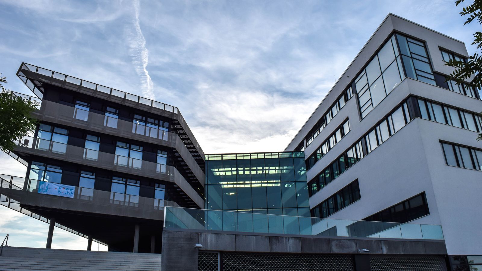 A modern glass-facade building against a blue sky, featuring innovative architecture.