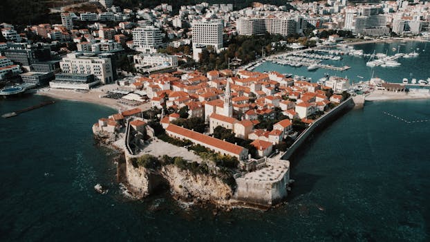 Aerial view of Budva's picturesque old town with red tile roofs, citadel, and seaside harbor.