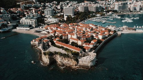 Free Aerial view of Budva's picturesque old town with red tile roofs, citadel, and seaside harbor. Stock Photo
