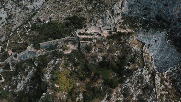 Drone shot capturing the ancient fortress nestled in the rugged hills of Kotor, Montenegro.
