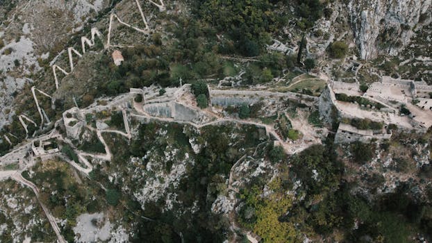 A stunning aerial view of the ancient fortress in Kotor, Montenegro showcasing zigzagging paths and stone ruins.