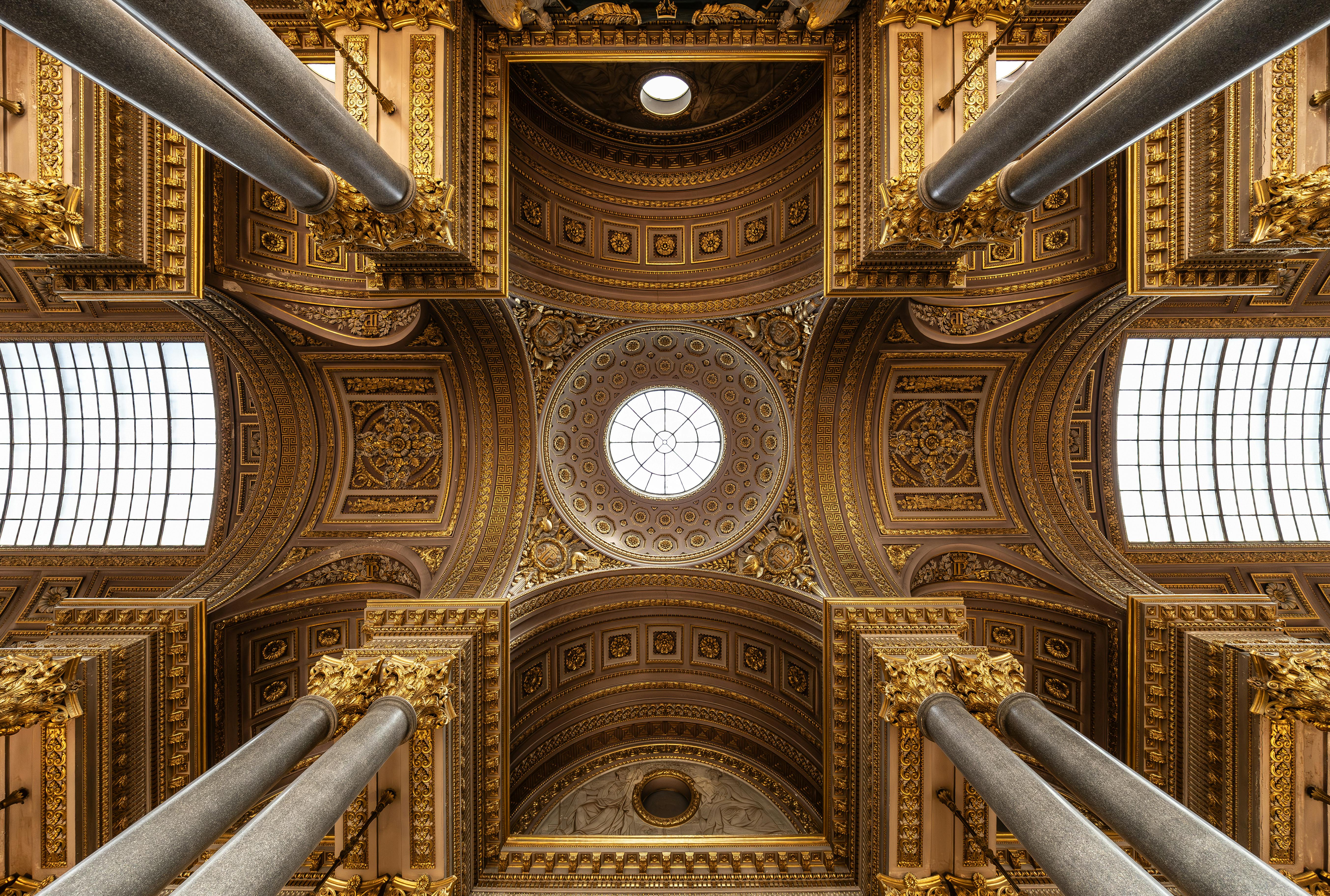 Detailed view of the ornate ceiling in the Palace of Versailles featuring golden patterns and columns.