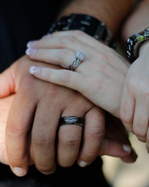 Crop unrecognizable married couple with wedding rings and massive bracelets holding hands to support and comfort each other