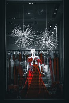 Stylish red dress displayed on mannequin in fashionable clothing store window.