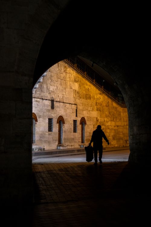 Free Silhouette of a person walking under a lit tunnel in Istanbul at night. Stock Photo