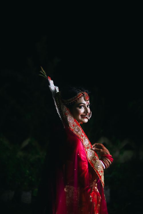 Free A stunning portrait of a smiling bride in traditional red wedding dress captured at night. Stock Photo