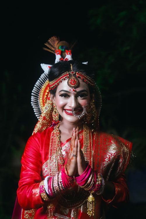 Free A radiant bride in traditional red attire smiling warmly, showcasing vibrant cultural jewelry and makeup. Stock Photo