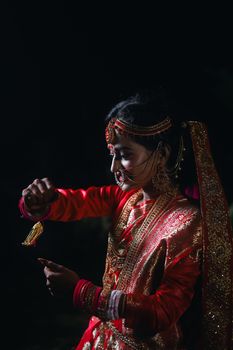 Close-up portrait of an Indian bride in ornate red and gold sari, showcasing intricate jewelry.